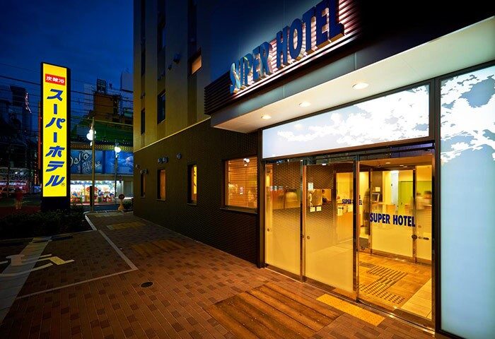 Exterior of Super Hotel Shinjuku Kabukicho, a gay-friendly hotel. Entrance at night with illuminated sign. Popular choice for gay travelers.