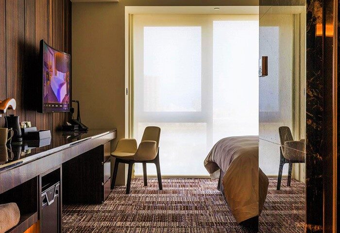 Suz Hotel gay-friendly room: Desk with TV, chair, and bed visible. Modern design. Ideal for gay travel. Interior of Suz Hotel room.