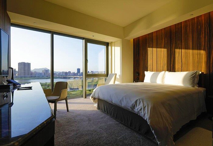 Suz Hotel room with city view. Gay-friendly hotel featuring modern design, large windows, comfortable bed. Ideal for gay travelers seeking stylish accommodations.