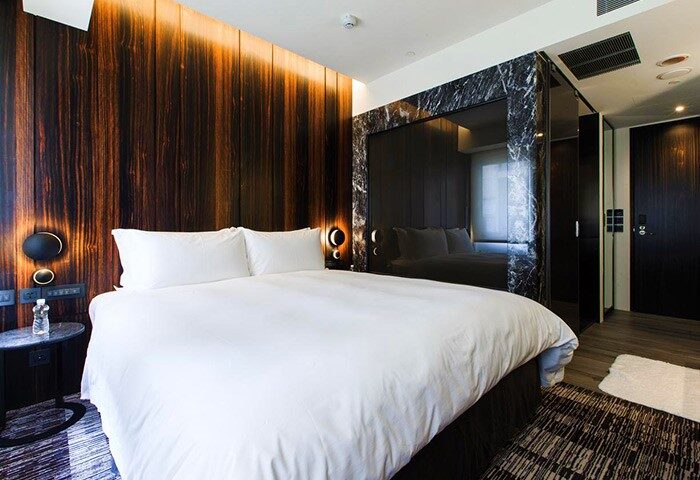Suz Hotel: Gay-friendly hotel room with a large bed, wood paneling, and modern design. A comfortable and stylish choice for gay travelers.