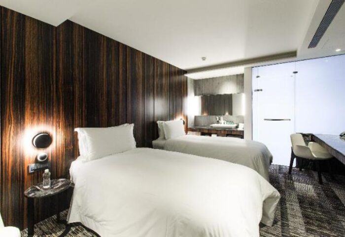 Suz Hotel's gay-friendly room with two beds, wood paneling, and a modern bathroom. Ideal lodging for gay travelers seeking comfort.