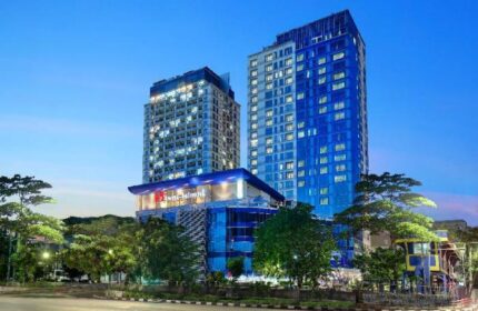 Swiss-Belhotel Mangga Besar exterior view at dusk. Gay-friendly hotel in Jakarta, Indonesia. Modern architecture, blue & white towers.