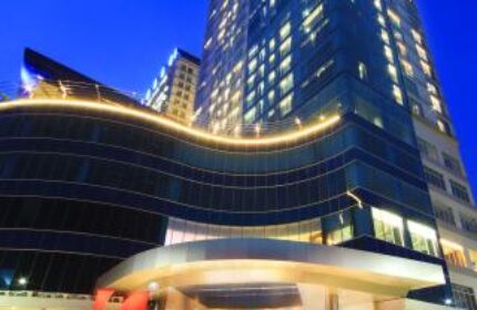 Swiss-Belhotel Mangga Besar, a gay-friendly hotel in Jakarta. The hotel's exterior is lit up at night, showcasing its modern design.