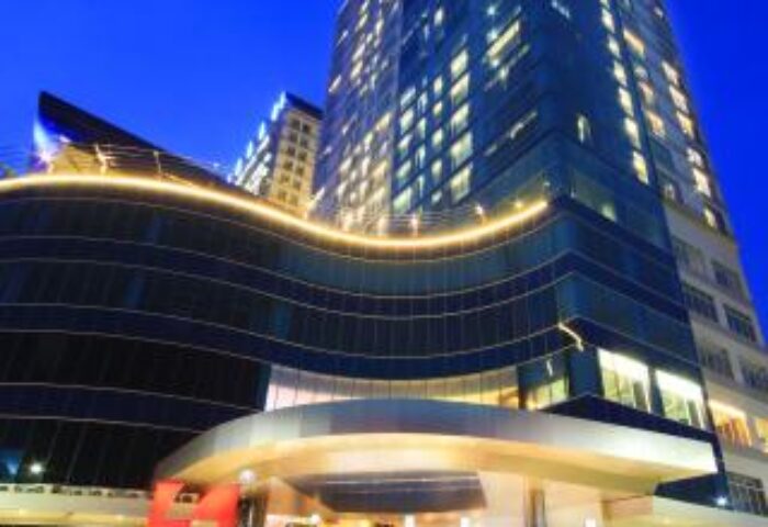 Swiss-Belhotel Mangga Besar, a gay-friendly hotel in Jakarta. The hotel's exterior is lit up at night, showcasing its modern design.