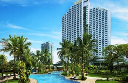 Swiss-Belhotel Mangga Besar exterior view. Gay-friendly hotel with pool, palm trees, and modern architecture in Jakarta, Indonesia.