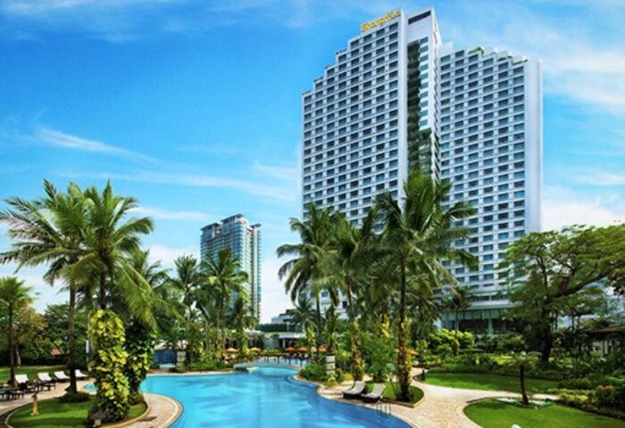 Swiss-Belhotel Mangga Besar exterior view. Gay-friendly hotel with pool, palm trees, and modern architecture in Jakarta, Indonesia.