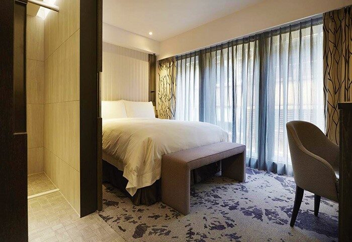 TANGO INN TAIPEI XIMEN gay-friendly hotel room. Modern design with a king bed, bench, chair, and bathroom. Perfect for gay travelers in Taipei.