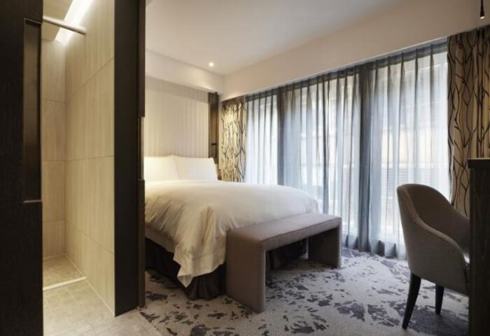 TANGO INN Taipei Ximen gay-friendly hotel room. Modern design, bed, chair, and shower visible. Comfortable stay for gay travelers.