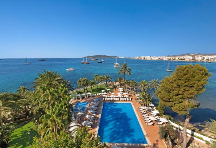 THB Los Molinos Adults Only: Gay-friendly hotel pool and ocean view. Santa Eularia, Ibiza. Ideal for gay travel. Palm trees and lounge chairs.