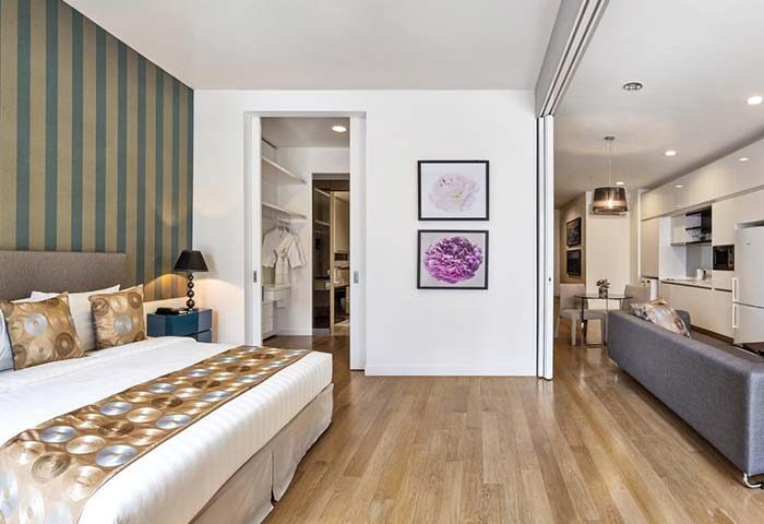 THE FACE Suites Kuala Lumpur room. Gay-friendly hotel with bedroom, living area, and kitchenette. Modern design, wood floors.