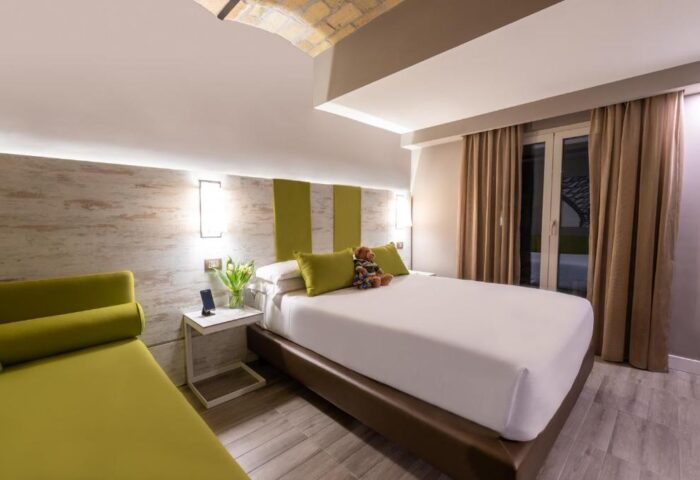 Gay-Friendly Hotel room at The Guardian: Modern decor, king bed with teddy bear, green accents, and a cozy daybed. Ideal gay men travel advice.