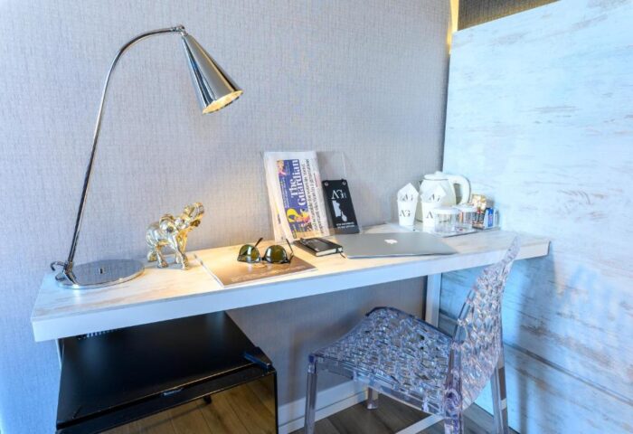 Gay-friendly hotel room desk with The Guardian newspaper, laptop, and tea set. Modern design for gay travel, comfortable stay.
