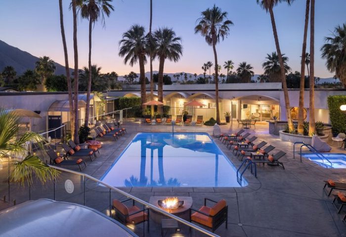 Palm Springs Hotel pool at dusk. Gay-friendly hotel with lounge chairs, palm trees, and fire pit. A relaxing desert oasis.