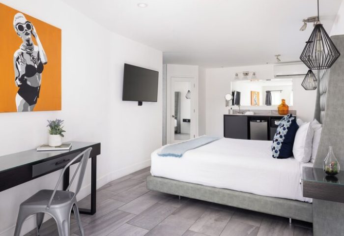 Gay-Friendly Hotel THE PALM SPRINGS HOTEL room. Modern design with orange art, desk, TV, & a peek into the bathroom. Stylish Palm Springs stay.