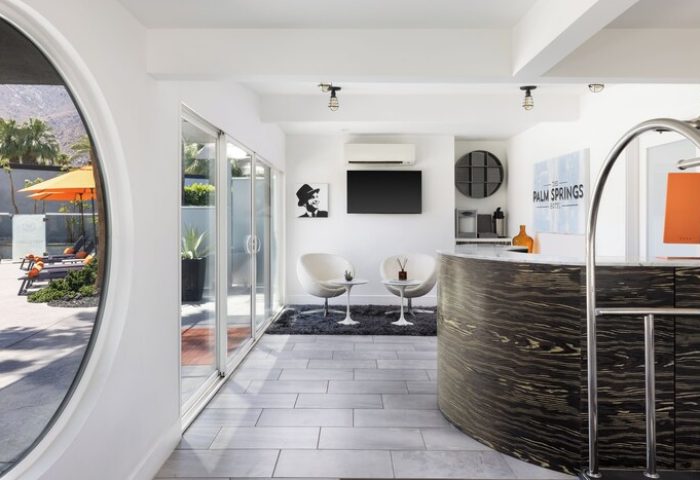Palm Springs Hotel lobby. Modern design, reception desk, lounge chairs, and a glimpse of the pool area. Gay-friendly hotel for discerning travelers.