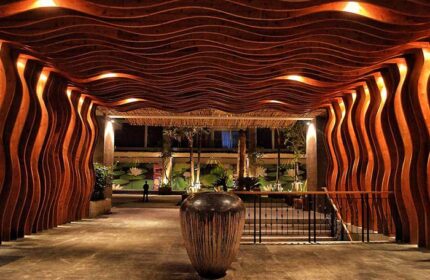 TS Suites Seminyak gay-friendly hotel entrance. Unique wood design, warm lighting, and tropical plants create an inviting atmosphere.
