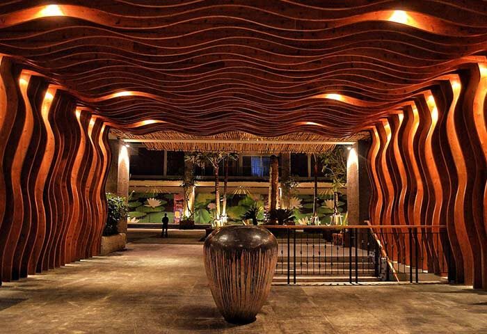 TS Suites Seminyak gay-friendly hotel entrance. Unique wood design, warm lighting, and tropical plants create an inviting atmosphere.