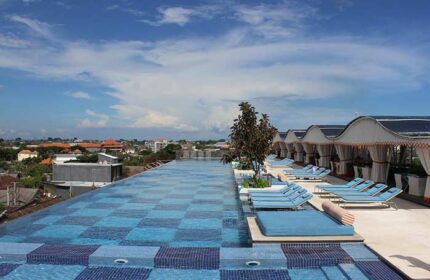 TS Suites Seminyak gay-friendly hotel rooftop pool view. Relaxing blue loungers and cabanas overlook the city skyline. Perfect for gay travel.