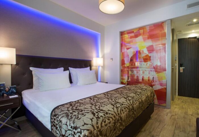 TWO Hotel Berlin by Axel room. Gay-friendly adults-only hotel with modern design, blue lighting, comfortable bed, and artistic decor.