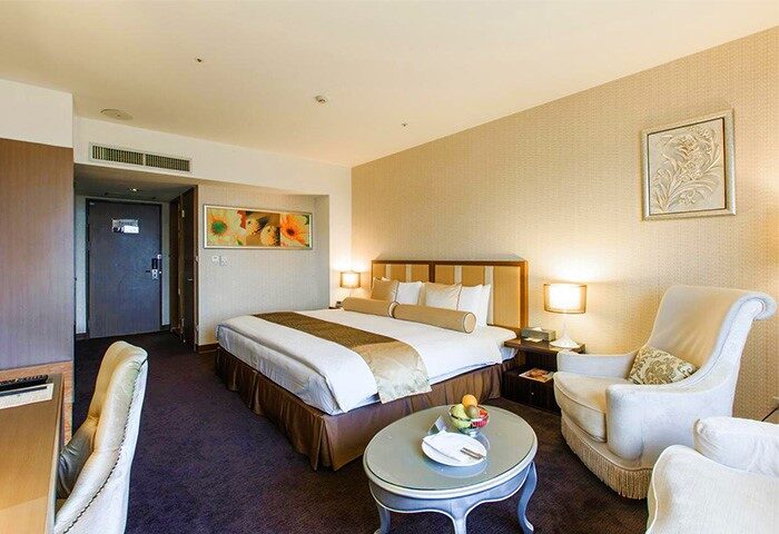 Taipei Garden Hotel room. Gay-friendly hotel bedroom with king bed, sitting area, fruit plate. Comfortable stay for gay travelers in Taipei.