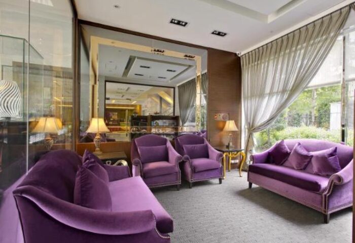 Taipei Garden Hotel lounge area. Purple velvet sofas and armchairs. Gay-friendly hotel with elegant decor. Relaxing space for LGBTQ+ travelers.