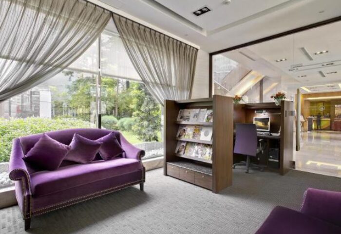Taipei Garden Hotel lobby with purple velvet seating, bookcase, and computer station. A gay-friendly hotel in Taipei for LGBTQ+ travelers.