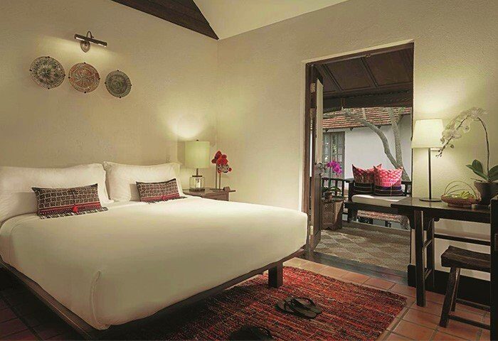 Tamarind Village Hotel room with balcony. Gay-friendly hotel featuring a bed, desk, and outdoor seating. Chiang Mai travel for gay men.