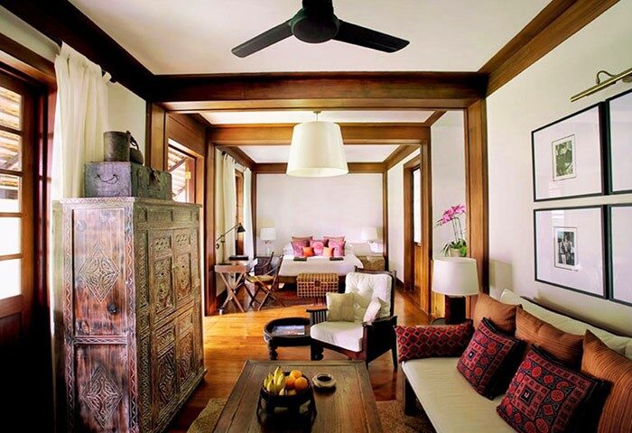 Gay-friendly Tamarind Village Hotel room. The bedroom features a bed, desk, couch, and a carved wooden cabinet. Chiang Mai, Thailand.