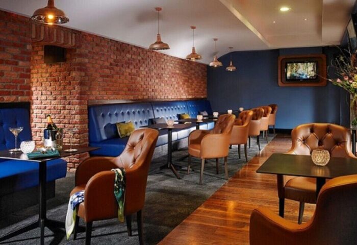 Temple Bar Hotel's stylish interior. Gay-friendly hotel with brick walls, blue booths, leather chairs, and modern lighting. Dublin's charm.