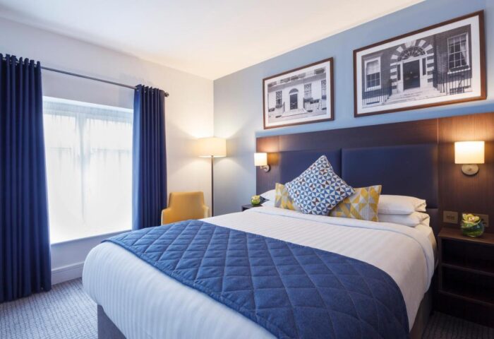 Temple Bar Hotel gay-friendly room. Double bed with blue accents, bedside table, and framed architectural prints. Dublin gay travel.