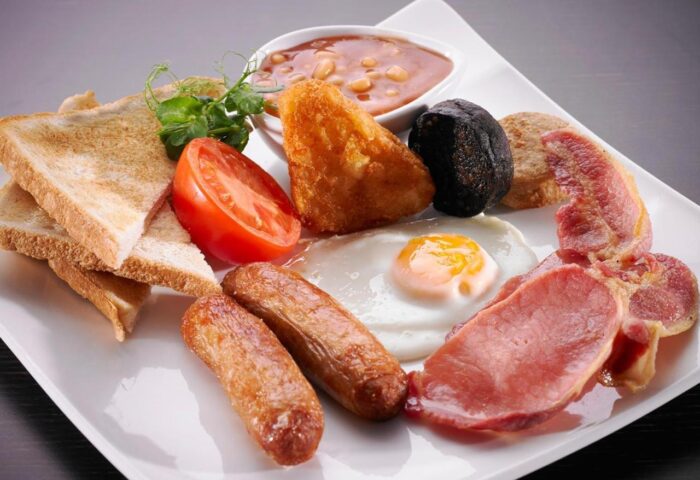 Full Irish breakfast at gay-friendly Temple Bar Hotel. Plate with sausages, bacon, egg, beans, tomato, toast, and black & white pudding.