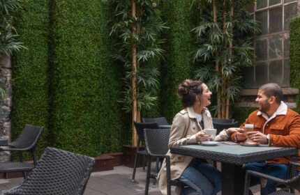 Temple Bar Inn, a gay-friendly hotel. Couple enjoying coffee at an outdoor cafe. Lush green wall and bamboo add to the ambiance. Dublin travel.