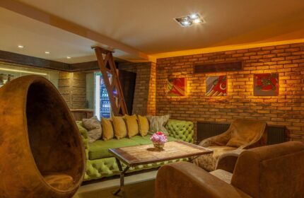 Temple Bar Inn, gay-friendly hotel. Cozy lounge area with brick wall, egg chair, green sofa, and leather armchairs. Dublin gay travel.