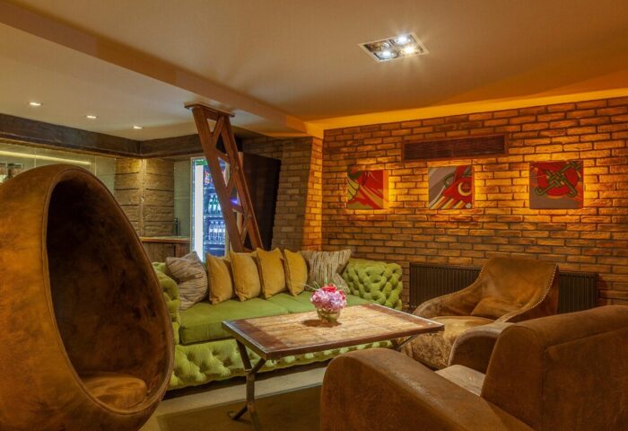 Temple Bar Inn, gay-friendly hotel. Cozy lounge area with brick wall, egg chair, green sofa, and leather armchairs. Dublin gay travel.