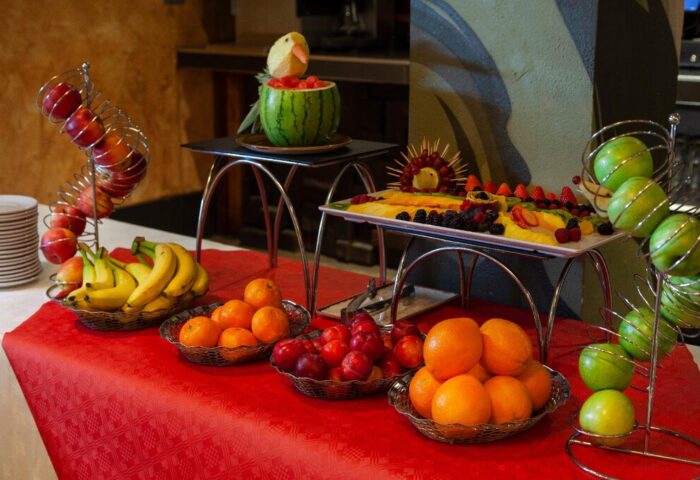 Fruit display at Temple Bar Inn, a gay-friendly hotel. Watermelon carving, fruit platters, apples, oranges, bananas, and plums on a red tablecloth.