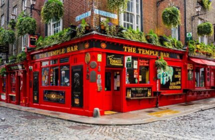 Temple Bar Lane by The KeyCollections. Dublin's famous Temple Bar, a gay-friendly hotel, with its vibrant red facade and lush greenery.