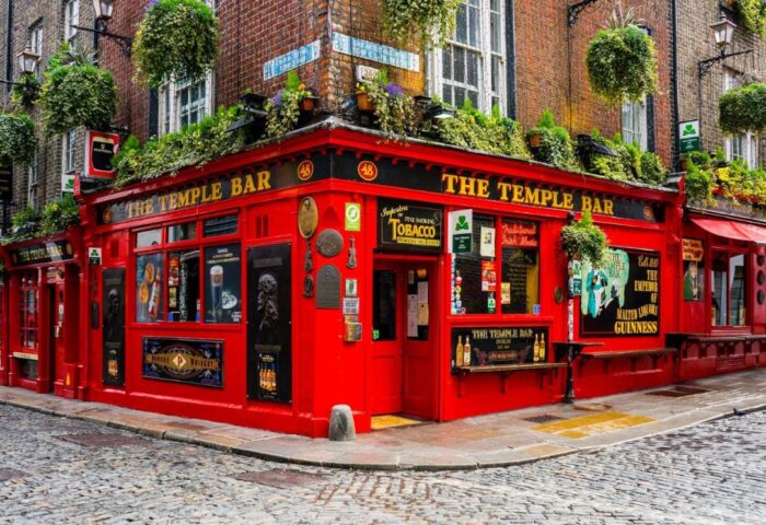Temple Bar Lane by The KeyCollections. Dublin's famous Temple Bar, a gay-friendly hotel, with its vibrant red facade and lush greenery.