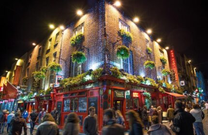 Temple Bar Lane by the KeyCollections: A gay-friendly hotel in Dublin, Ireland. The Temple Bar pub glows with lights at night, attracting crowds.