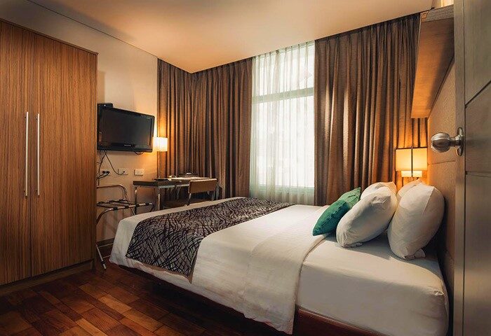 The A. Venue Hotel room. Gay-friendly hotel with bed, pillows, TV, desk, and wardrobe. Modern design for gay travel in a comfortable space.