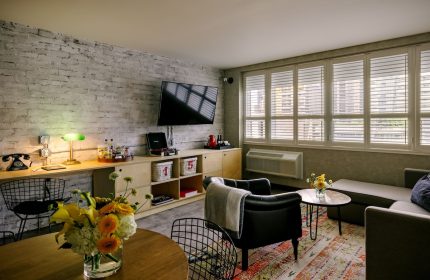 The Anndore House, part of JVD by Hyatt, a gay-friendly hotel. Room interior with brick wall, TV, record player, and seating area.