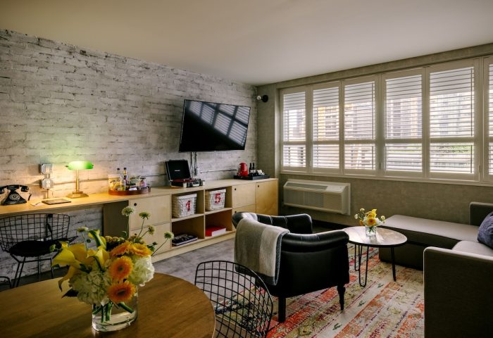 The Anndore House, part of JVD by Hyatt, a gay-friendly hotel. Room interior with brick wall, TV, record player, and seating area.