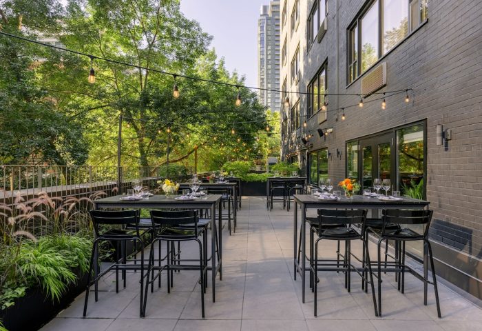 Outdoor patio at The Anndore House, part of JVD by Hyatt, a gay-friendly hotel. Tables, chairs, greenery, and string lights create a welcoming space.