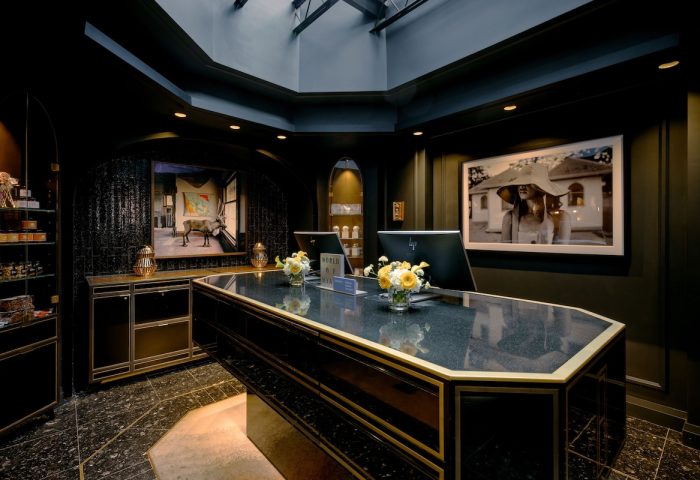 The Anndore House, part of JVD by Hyatt, a gay-friendly hotel. Lobby with a dark desk, flowers, and art. Great for gay men travel.