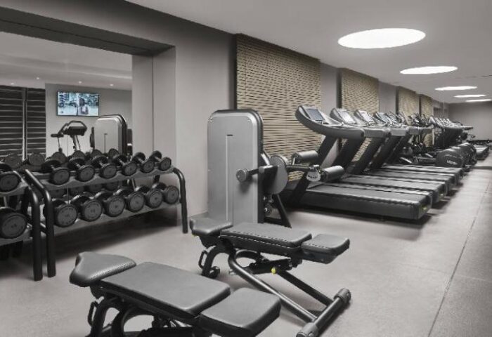 Gym at The Barcelona EDITION, a gay-friendly hotel. Dumbbells, weight machines, and treadmills for a workout. Modern fitness center.