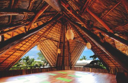 Yoga space at The Beach Tulum Hotel, a gay-friendly hotel. Thatched roof, wooden floor, and yoga mats. Tropical view from this Tulum hotel.