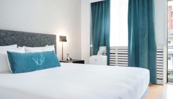 The Burrard Hotel's gay-friendly room. Modern design with a king-size bed, teal accents, and city view. Ideal for gay travelers.