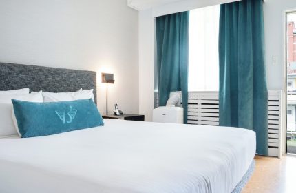 The Burrard Hotel's gay-friendly room. Modern design with a king-size bed, teal accents, and city view. Ideal for gay travelers.