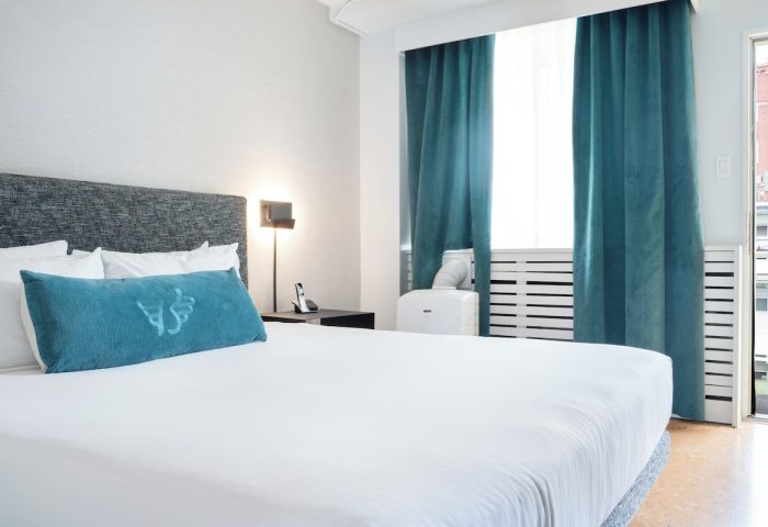 The Burrard Hotel's gay-friendly room. Modern design with a king-size bed, teal accents, and city view. Ideal for gay travelers.