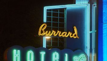 The Burrard Hotel's neon sign at night. Gay-friendly hotel with retro design. Green Hotel lettering and a stylized swan. Vancouver, BC.