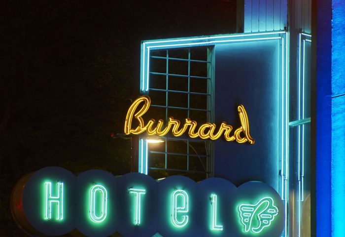 The Burrard Hotel's neon sign at night. Gay-friendly hotel with retro design. Green Hotel lettering and a stylized swan. Vancouver, BC.